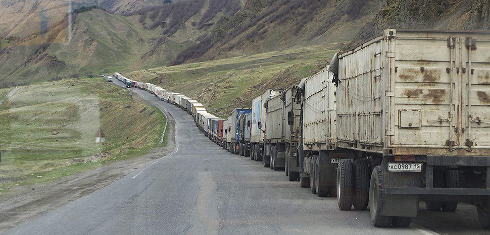 cc Clay Gilliland, modified, Line of trucks from Georgia and Armenia waiting to enter Russia Just south of Kazbegi; https://flickr.com/photos/26781577@N07/37109052573/in/photolist-YxcAtg-ezBaKz-oGJozX-oJt7qU-Zhzo9C-ZhznCs-2aTLqxG-CfJVAj-2aDbPpB-PRyLHG-gNSGzW-2aB2NVF-Zj3kMj-2bZC4UX-2bXuoHC-2nLvHZc-Zj3fxS-EnMPfs-DsohWo-DRC6vX-2kLVsmD-2kLRMmw-2iJ7FcS-2iJ7FgK-2iJ7Ffx-fhe3Cf-7orsHx-7ovmwS-PcL7bb-rm2mVZ-noiDg9-edhvaJ-2mcAJW2-2mcx3AR-edbRVF-ee7k1G-edbRQe-ecxge3-2gCFPBb-ee4wud-LVthDD-ecrCW2-KKgAvs-2gCFPGX-2gCFPEN-edbRCn-ecrD4X-dVgj8x-2mcWBES-afDKNz